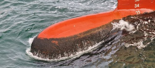 Ship hull with biofouling on ocean surface to be removed by Laserline diode lasers