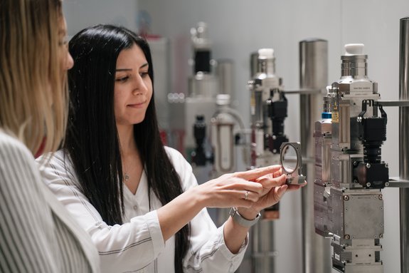 Employees explaining the function of optics in front of a display of different optics by Laserline diode lasers